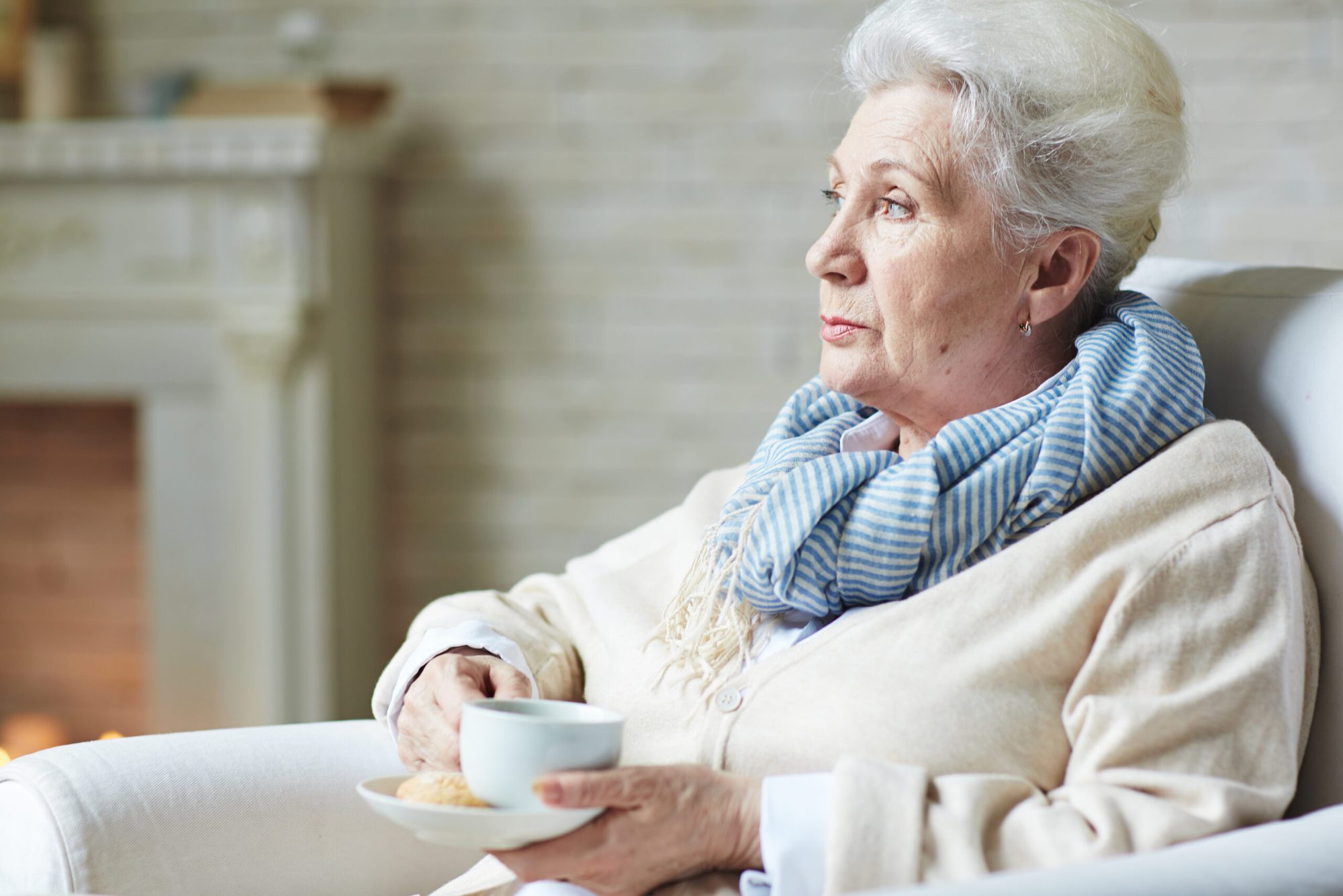 Seniorin genießt entspannt eine Tasse Tee im eigenen Wohnzimmer