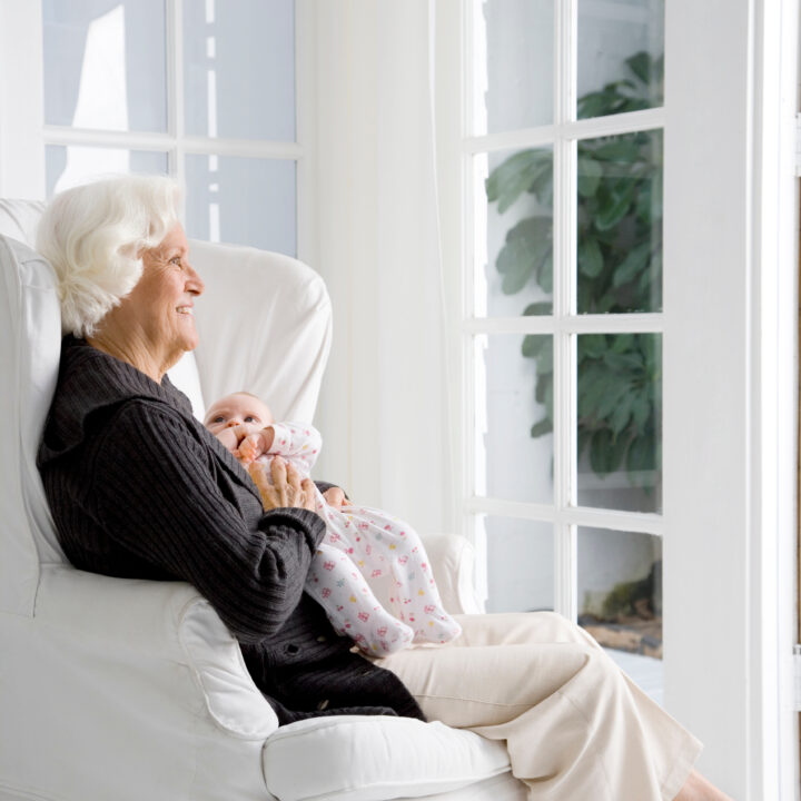 Großmutter hält liebevoll ihr neugeborenes Enkelkind im Arm